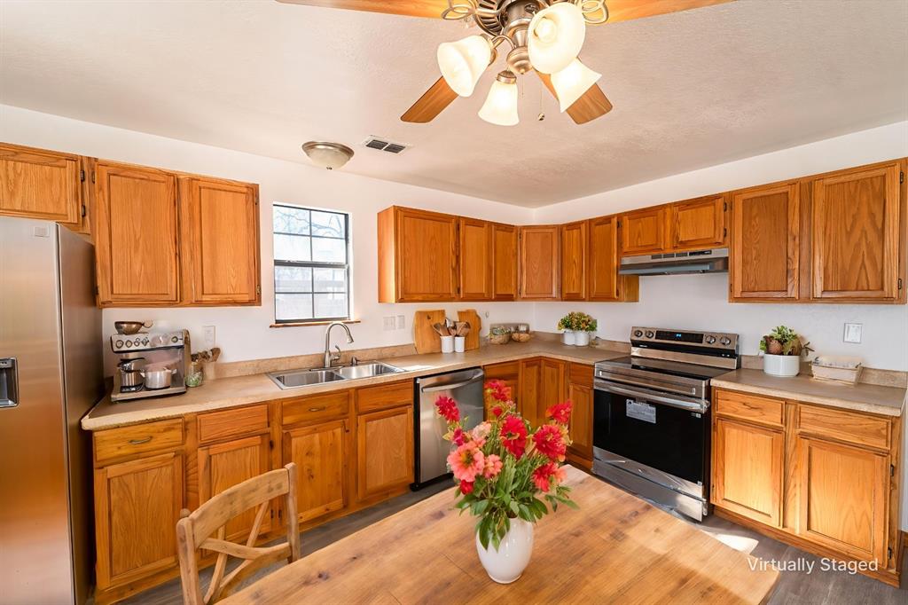 618 Oak Street Clyde, TX 79510 - Photo 11 of 39 a kitchen with stainless steel appliances granite countertop a sink dishwasher stove and refrigerator with wooden cabinets