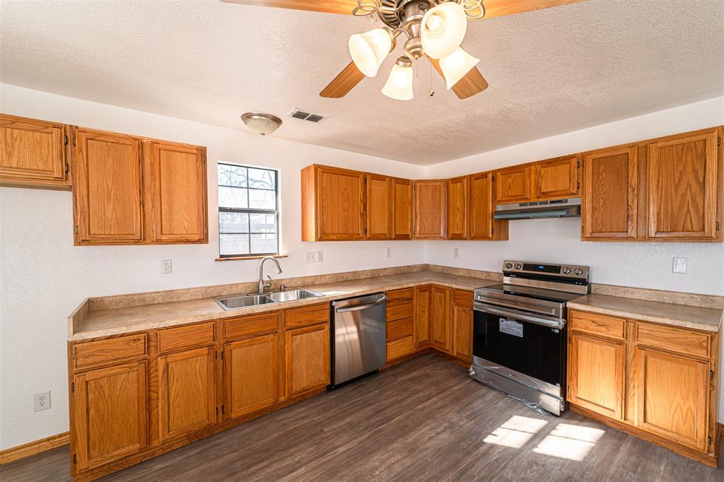 618 Oak Street Clyde, TX 79510 - Photo 12 of 39 a kitchen with stainless steel appliances granite countertop a sink dishwasher stove and refrigerator with wooden floor