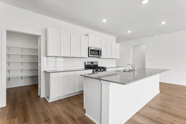 a kitchen with a sink a microwave a refrigerator and cabinets