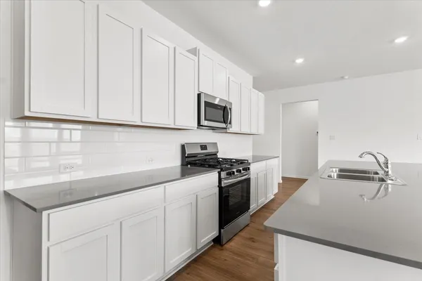 a kitchen with granite countertop white cabinets and stainless steel appliances