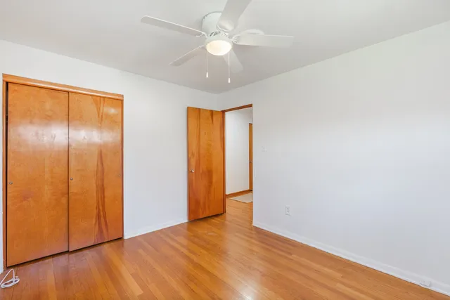 an empty room with wooden floor and a ceiling fan