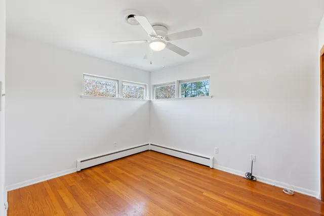 an empty room with wooden floor and ceiling fan