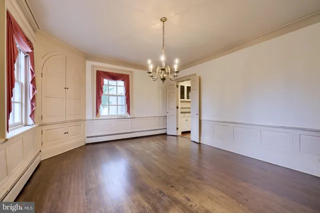 an empty room with wooden floor cabinet and windows