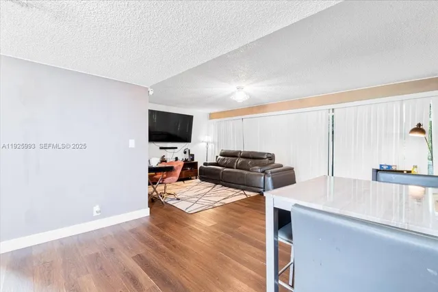 a view of a kitchen with kitchen island wooden floors appliances and living room view