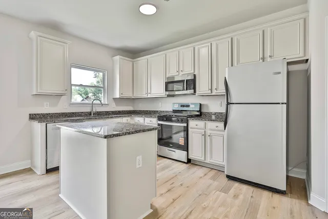 a kitchen with white cabinets white appliances and sink