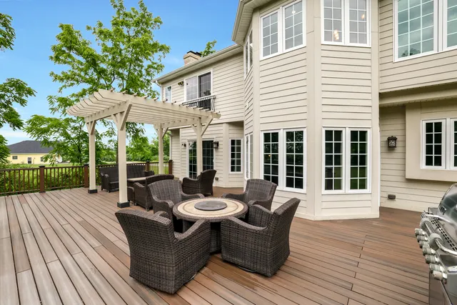 a view of a patio with couches and table and chairs with wooden floor and fence