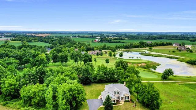 an aerial view of a residential houses with outdoor space and trees all around