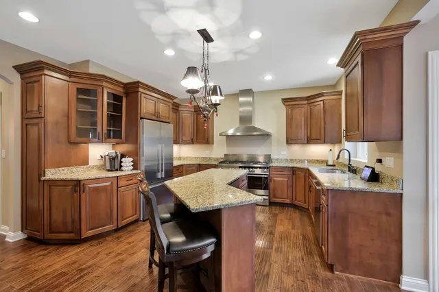 a kitchen with granite countertop a stove a sink dishwasher a dining table and chairs with wooden floor