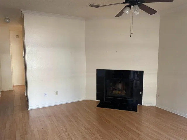 a view of an empty room with wooden floor and a fireplace