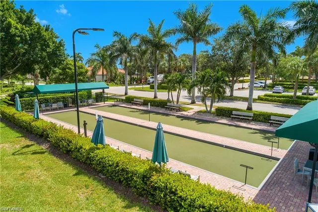 a view of a swimming pool with a lawn chairs and palm trees
