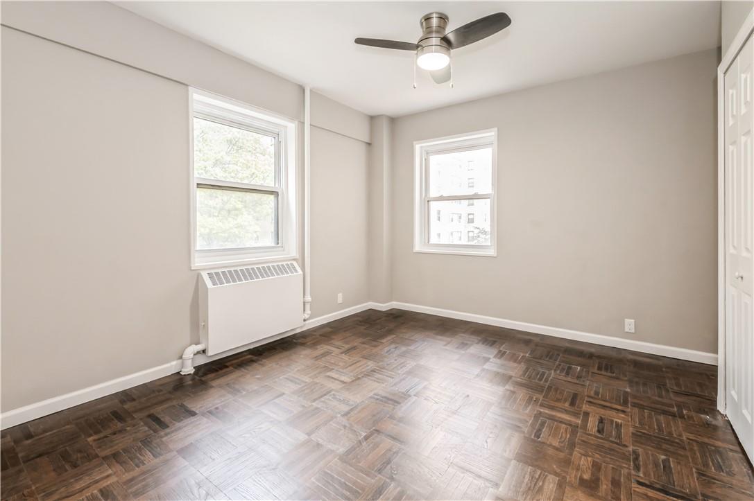 9 Fordham Hill Ovl, Unit 4F Bronx, NY 10468 - Photo 11 of 14 Spare room with radiator heating unit, dark parquet flooring, and ceiling fan