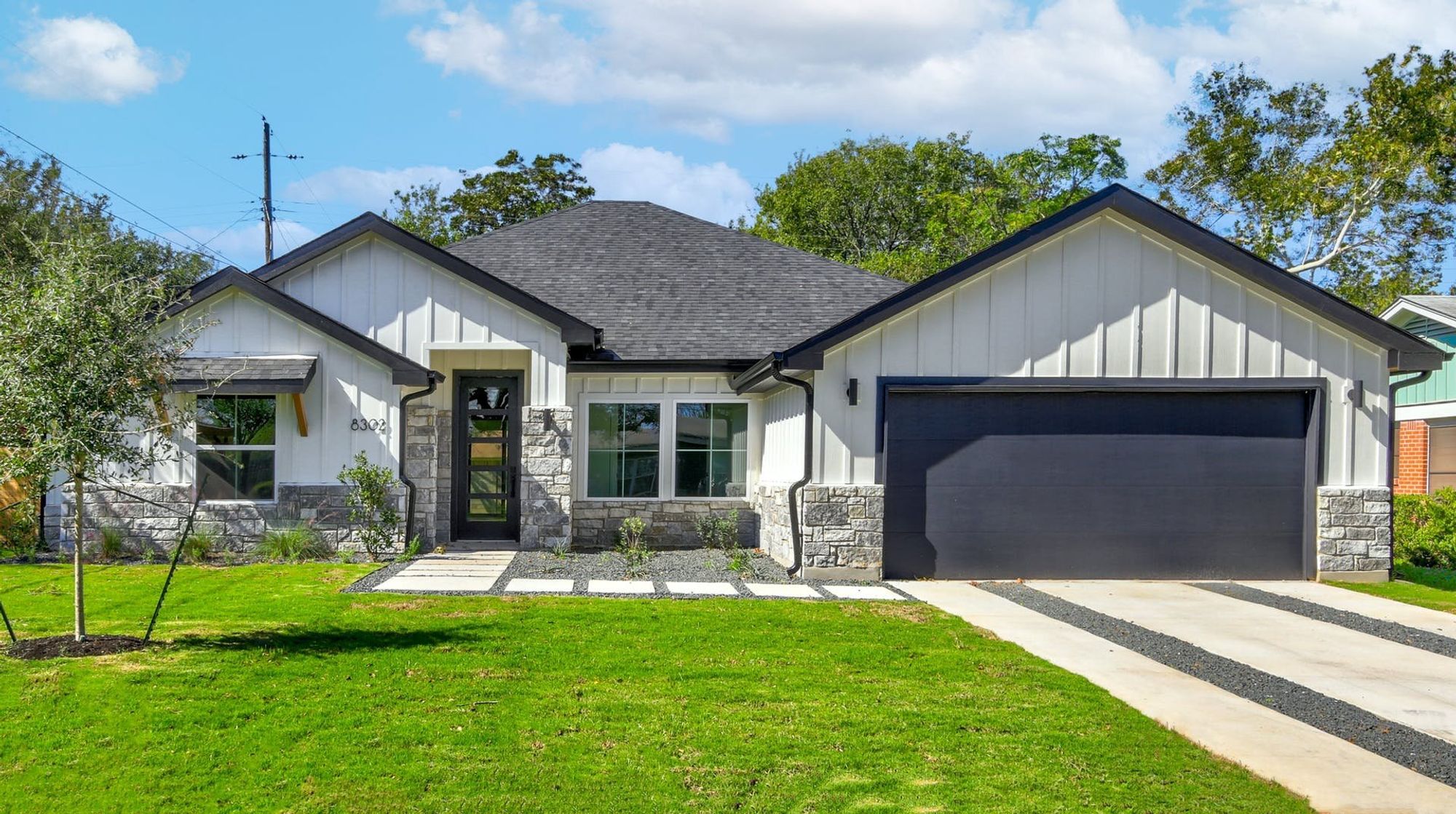 8302 Kromer Street Austin, TX 78757 - Photo 1 of 34 Modern inspired farmhouse featuring board and batten siding, a front lawn, a garage, and stone siding
