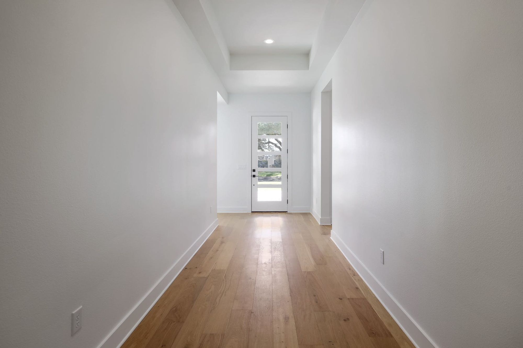 8302 Kromer Street Austin, TX 78757 - Photo 11 of 34 Hall featuring light wood-style flooring, a tray ceiling, and recessed lighting