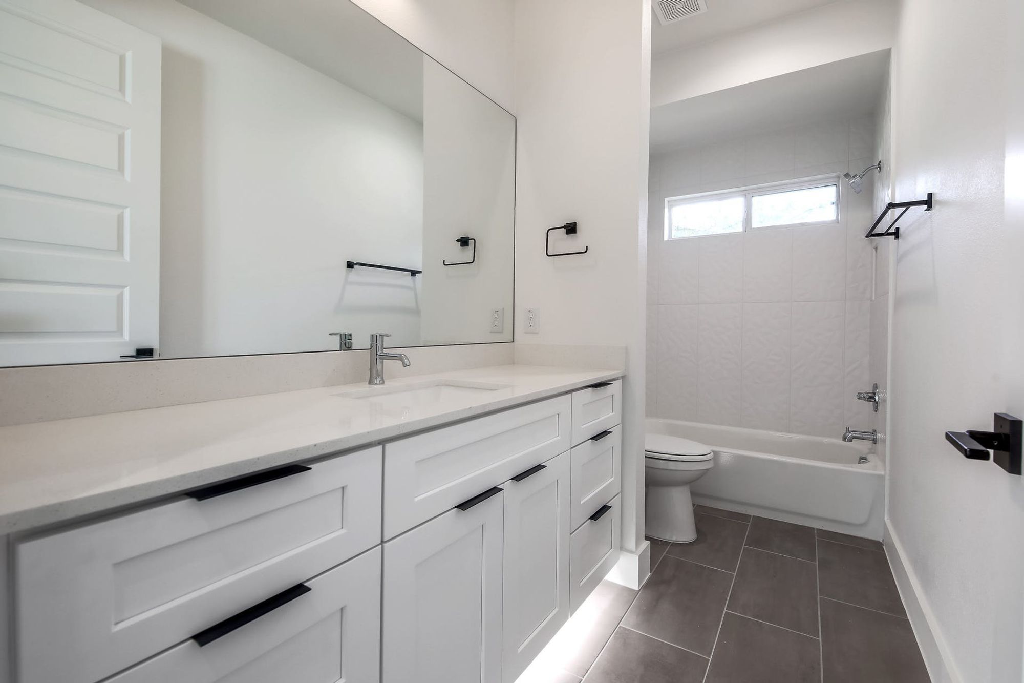 8302 Kromer Street Austin, TX 78757 - Photo 14 of 34 Full bath with vanity, washtub / shower combination, and dark tile patterned floors