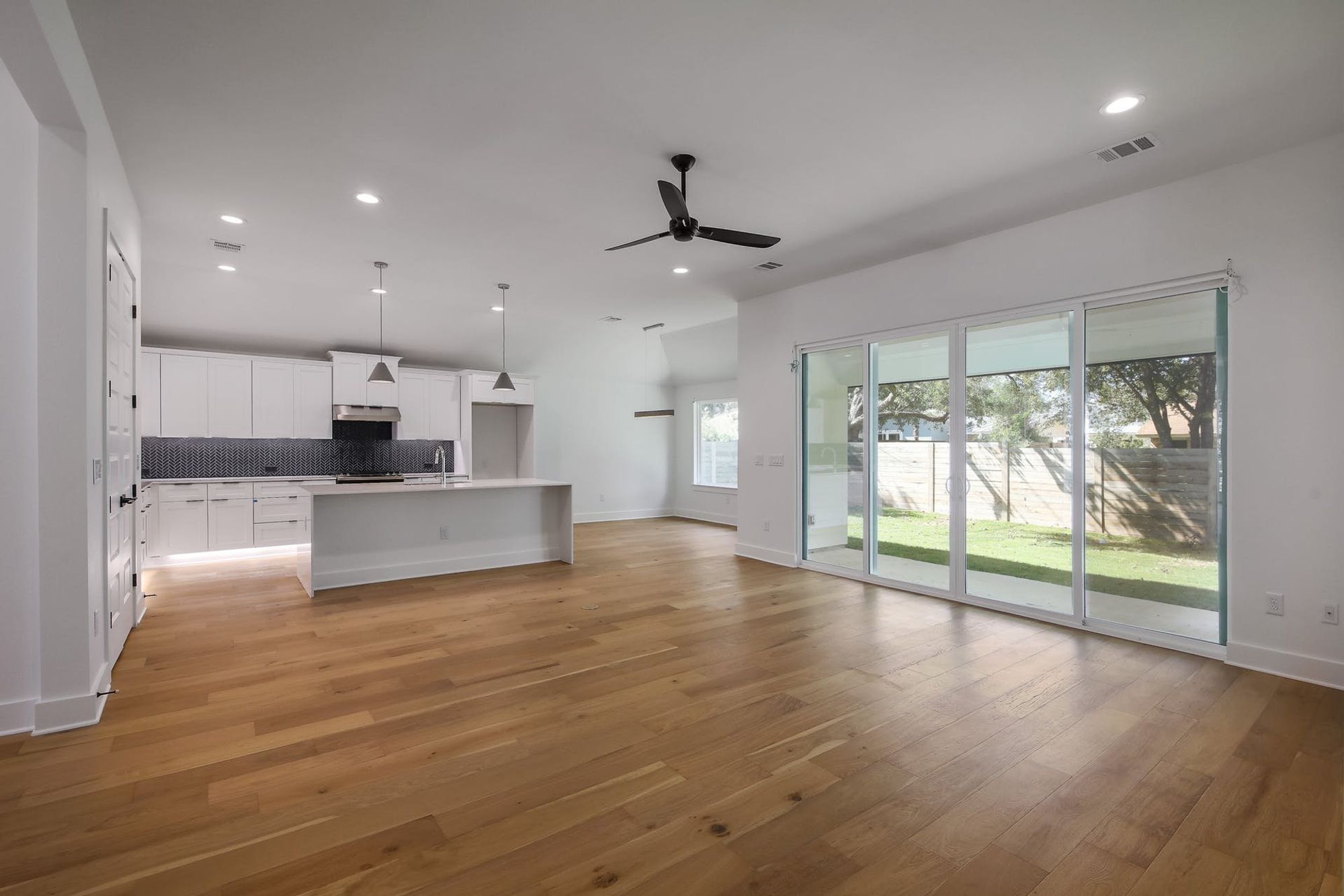 8302 Kromer Street Austin, TX 78757 - Photo 33 of 34 Kitchen with open floor plan, white cabinetry, a center island with sink, tasteful backsplash, and ceiling fan