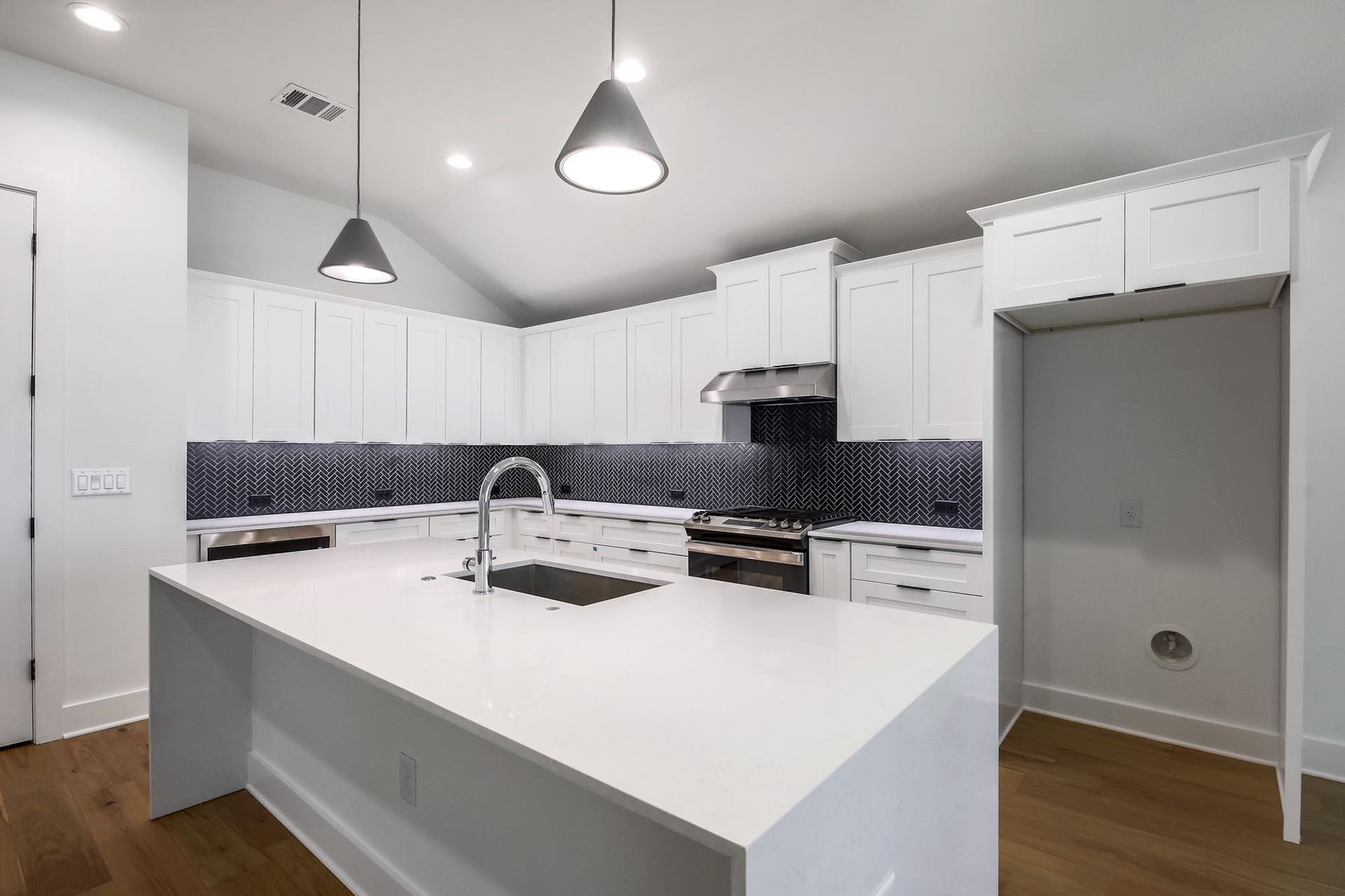 8302 Kromer Street Austin, TX 78757 - Photo 17 of 34 Kitchen featuring lofted ceiling, stainless steel range with gas cooktop, a kitchen island with sink, white cabinets, and dark wood finished floors