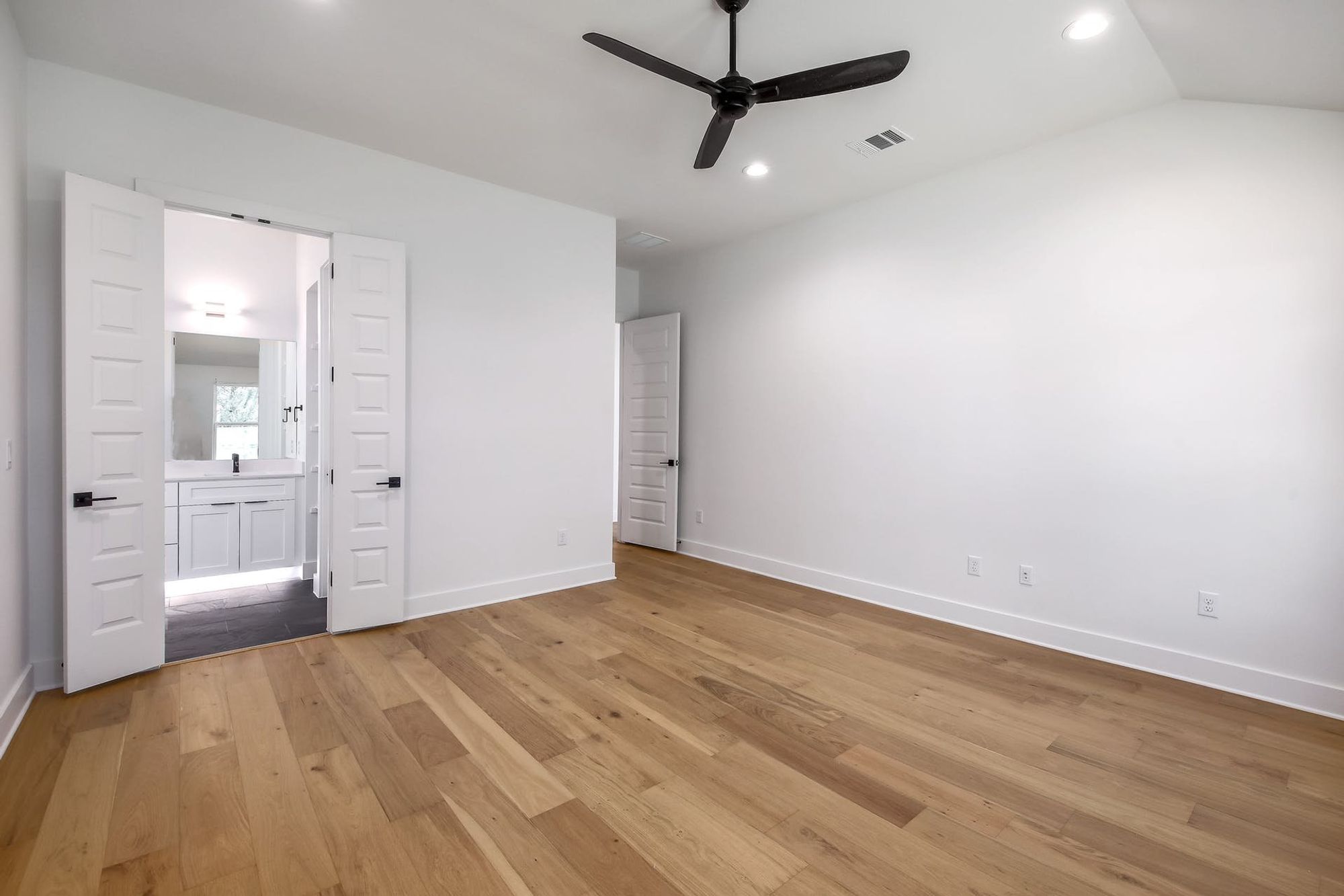 8302 Kromer Street Austin, TX 78757 - Photo 18 of 34 Unfurnished bedroom featuring ceiling fan, light wood-style floors, recessed lighting, and vaulted ceiling