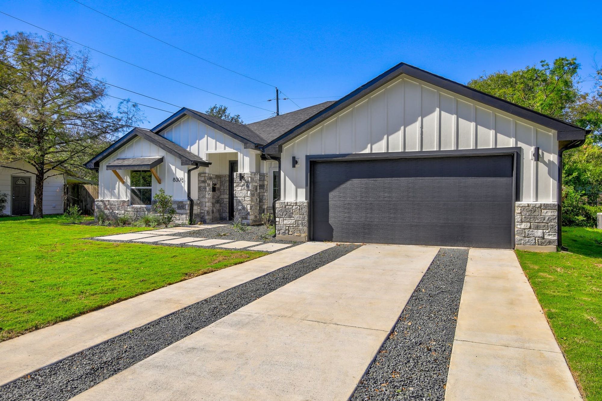 8302 Kromer Street Austin, TX 78757 - Photo 2 of 34 Modern inspired farmhouse featuring board and batten siding, stone siding, a front yard, and concrete driveway