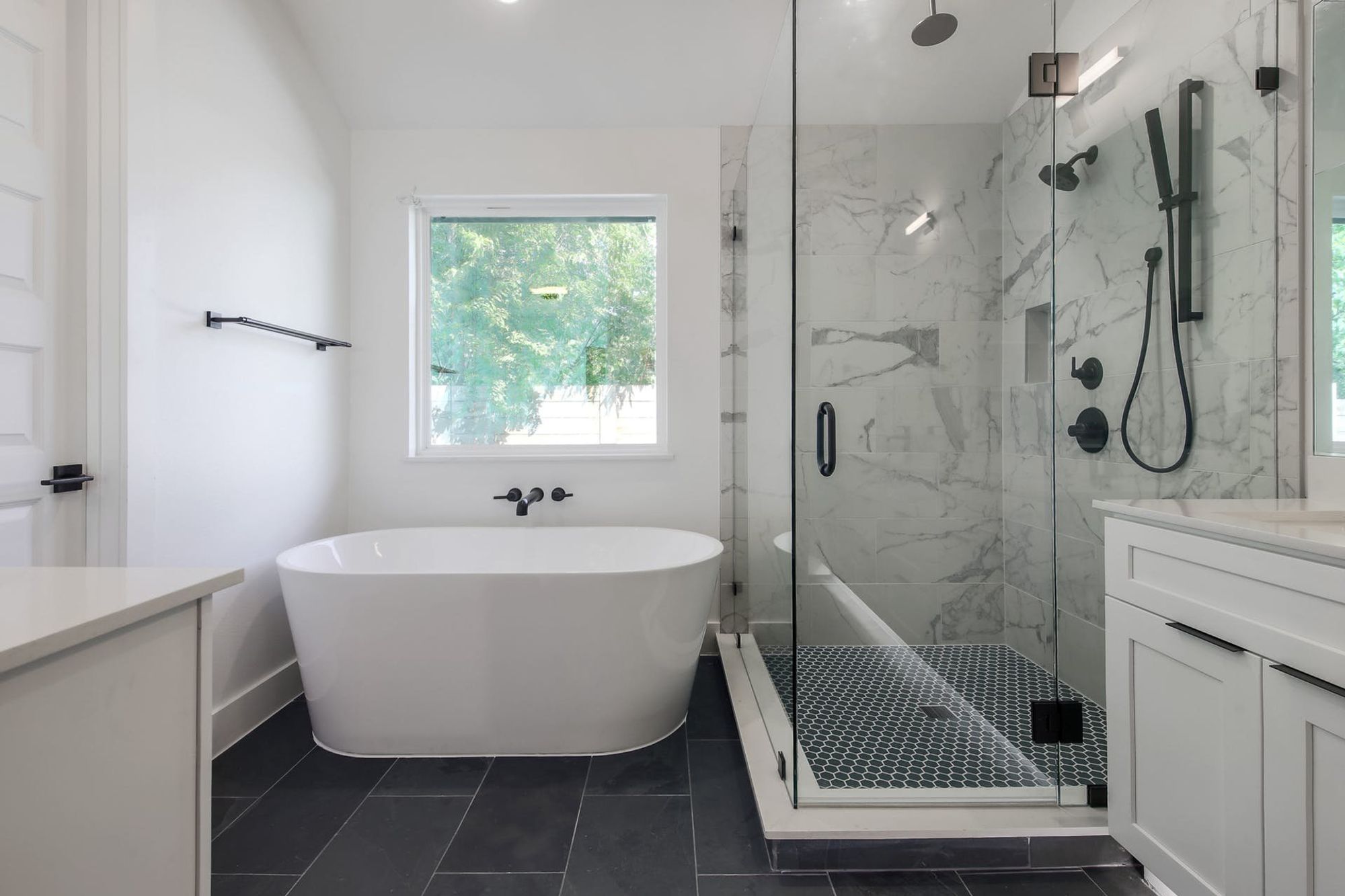 8302 Kromer Street Austin, TX 78757 - Photo 25 of 34 Full bath with vanity, a marble finish shower, a freestanding bath, and dark tile patterned floors