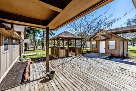a view of wooden floor with a table and chairs under an umbrella
