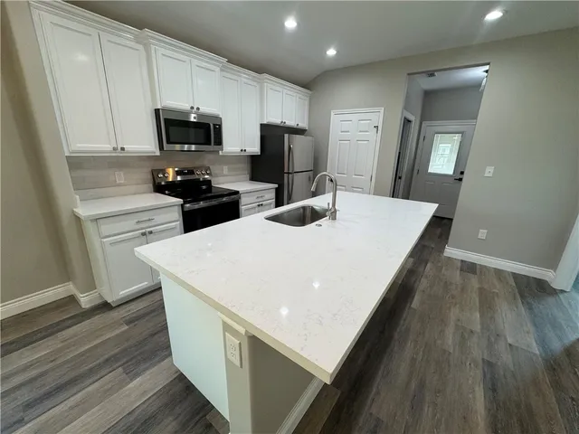 a kitchen with a sink a microwave a refrigerator and cabinets