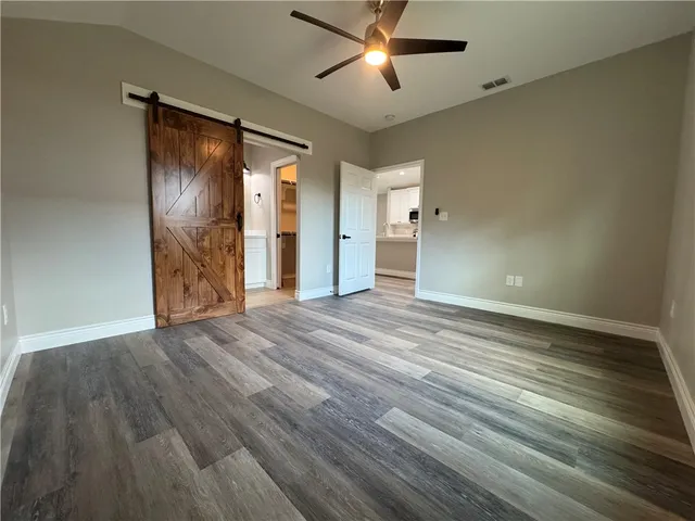 an empty room with wooden floor closet and windows