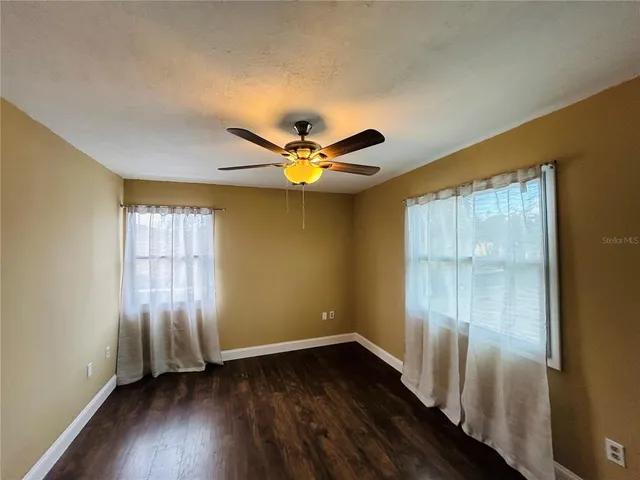 a view of an empty room with window and wooden floor