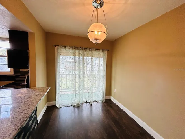 a kitchen with stainless steel appliances granite countertop a refrigerator a sink dishwasher a stove and a dining table with wooden floor