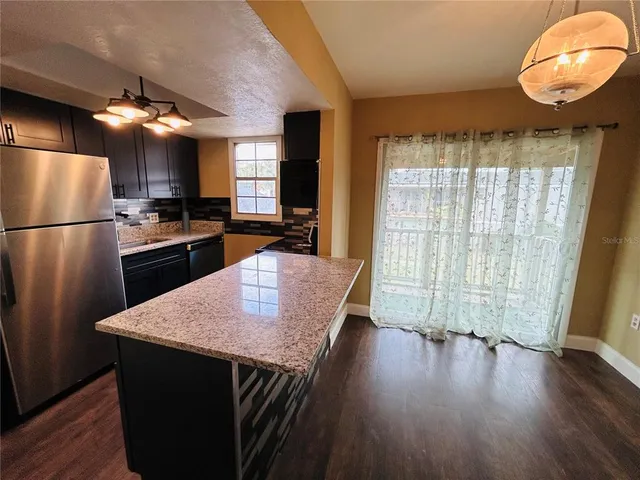 a kitchen with granite countertop stainless steel appliances a refrigerator microwave and stove