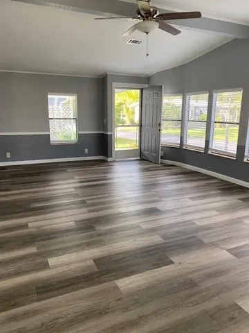 an empty room with wooden floor and windows