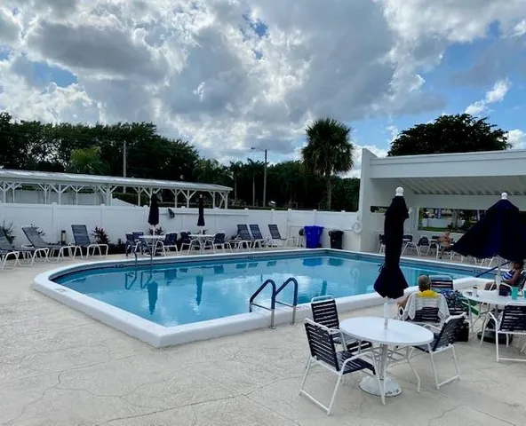 a swimming pool with outdoor seating and barbeque in the back