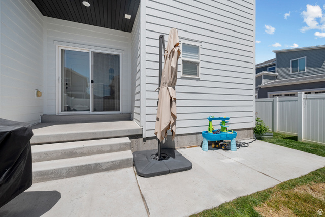 1708 North 1280th Street East Payson, UT 84651 - Photo 12 of 15 White siding exterior featuring a concrete patio with steps, a sliding glass door, a privacy fence, and a strip of green lawn