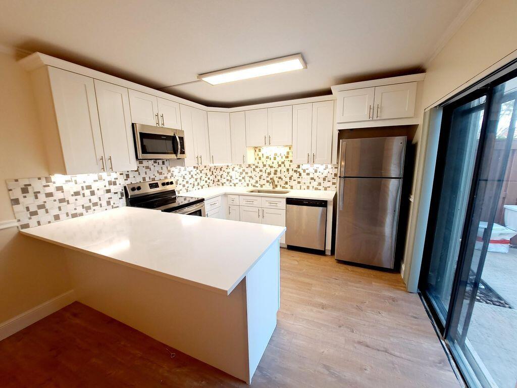 3900 County Line Road, Unit 16A Tequesta, FL 33469 - Photo 11 of 27 a kitchen with stainless steel appliances a refrigerator stove microwave and sink