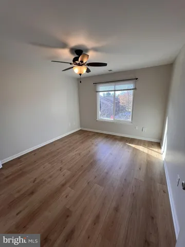 an empty room with wooden floor and a ceiling fan