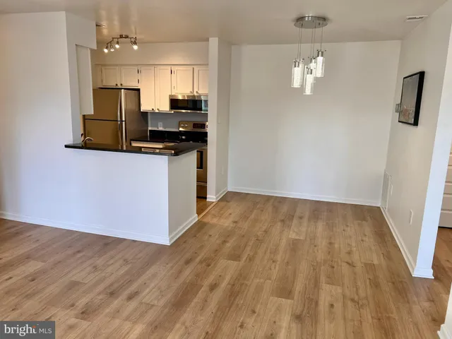 a view of kitchen and empty room with wooden floor