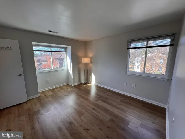an empty room with wooden floor and windows