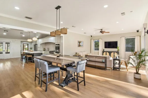 a view of a dining room and livingroom with furniture wooden floor a rug a fireplace and a chandelier