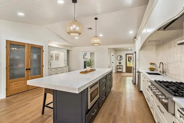 a large kitchen with lots of counter space a sink appliances and wooden floor
