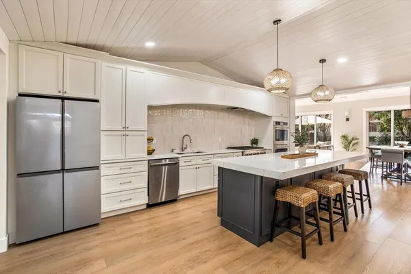 a kitchen with stainless steel appliances kitchen island granite countertop a table chairs and a refrigerator
