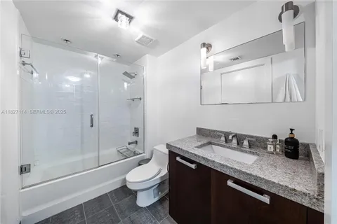 a bathroom with a granite countertop sink a toilet and shower