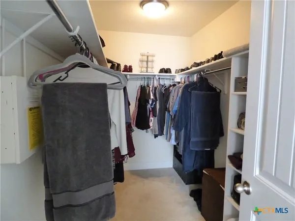 a view of walk in closet with clothes and shoes