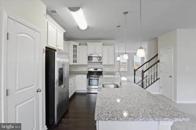 a kitchen with stainless steel appliances granite countertop a refrigerator a stove and a sink with wooden floor