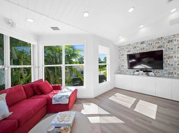 a living room with furniture a flat screen tv and floor to ceiling window