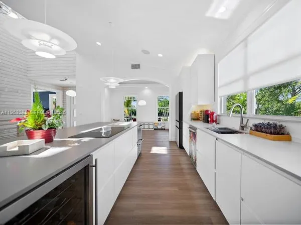 a large white kitchen with lots of counter space and wooden floor