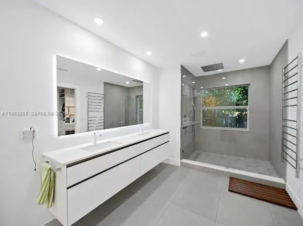 a spacious bathroom with a double vanity sink a mirror and a bathtub