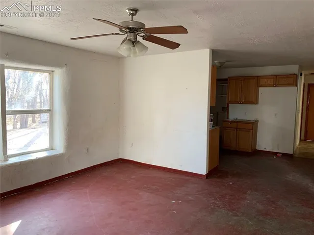 an empty room with windows and fan