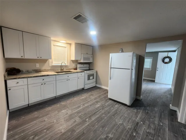 a kitchen with a refrigerator a sink and dishwasher with wooden floor