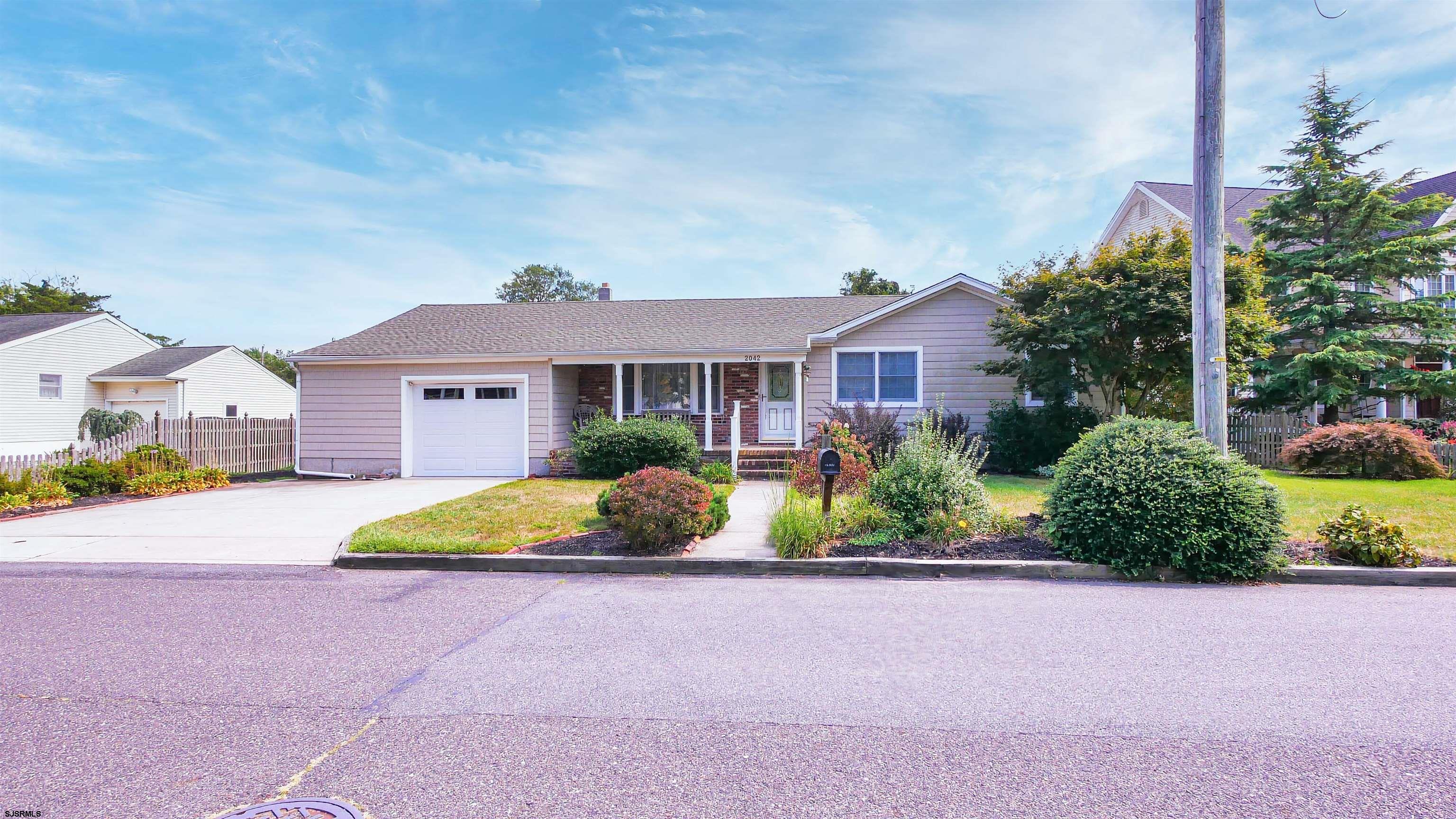 2042 Sutton Avenue Northfield, NJ 08225 - Photo 32 of 32 a front view of a house with a yard and potted plants