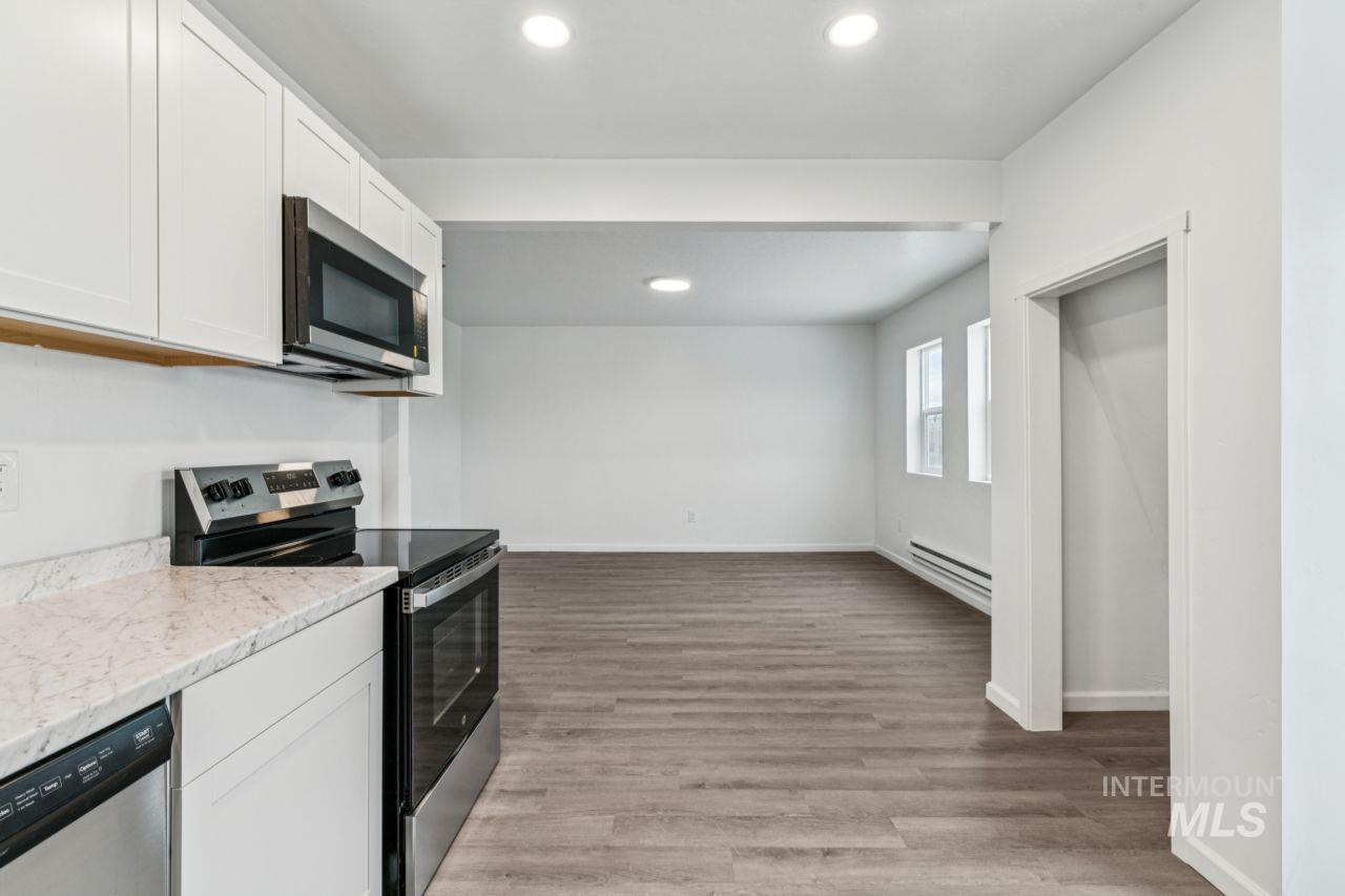 911 2nd Street South Nampa, ID 83651 - Photo 26 of 50 Kitchen featuring appliances with stainless steel finishes, white cabinets, recessed lighting, light wood-type flooring, and light stone counters
