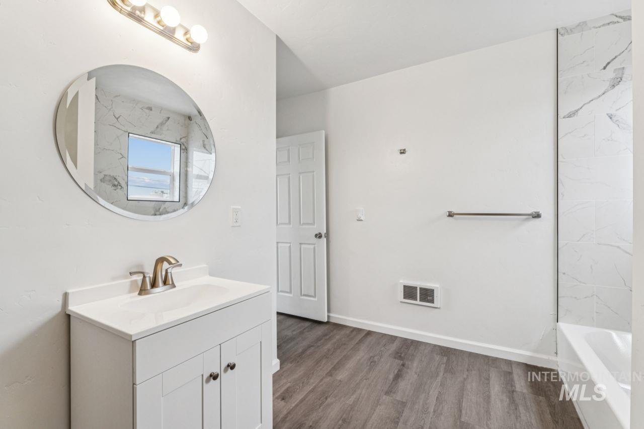 911 2nd Street South Nampa, ID 83651 - Photo 32 of 50 Full bath with vanity, wood finished floors, and bathing tub / shower combination